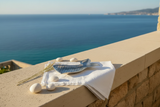 Vassoio decorativo a forma di coda di pesce in alluminio argento su terrazzo mediterraneo con vista mare